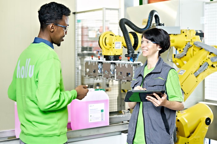 Zwei Menschen stehen neben einem Roboter in einer Fabrik.