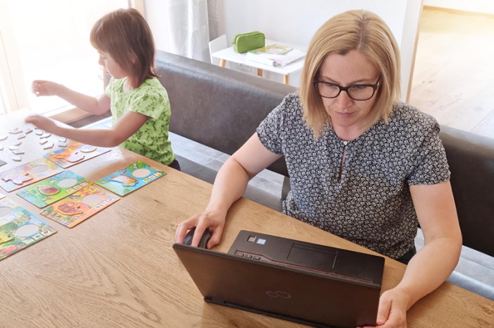 Eine Frau und ein Kind benutzen einen Laptop an einem Tisch.