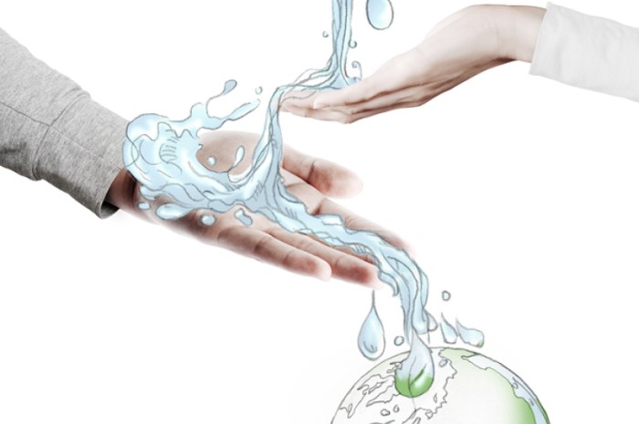 Eine Hand streckt sich nach einem Globus mit Wasser aus.