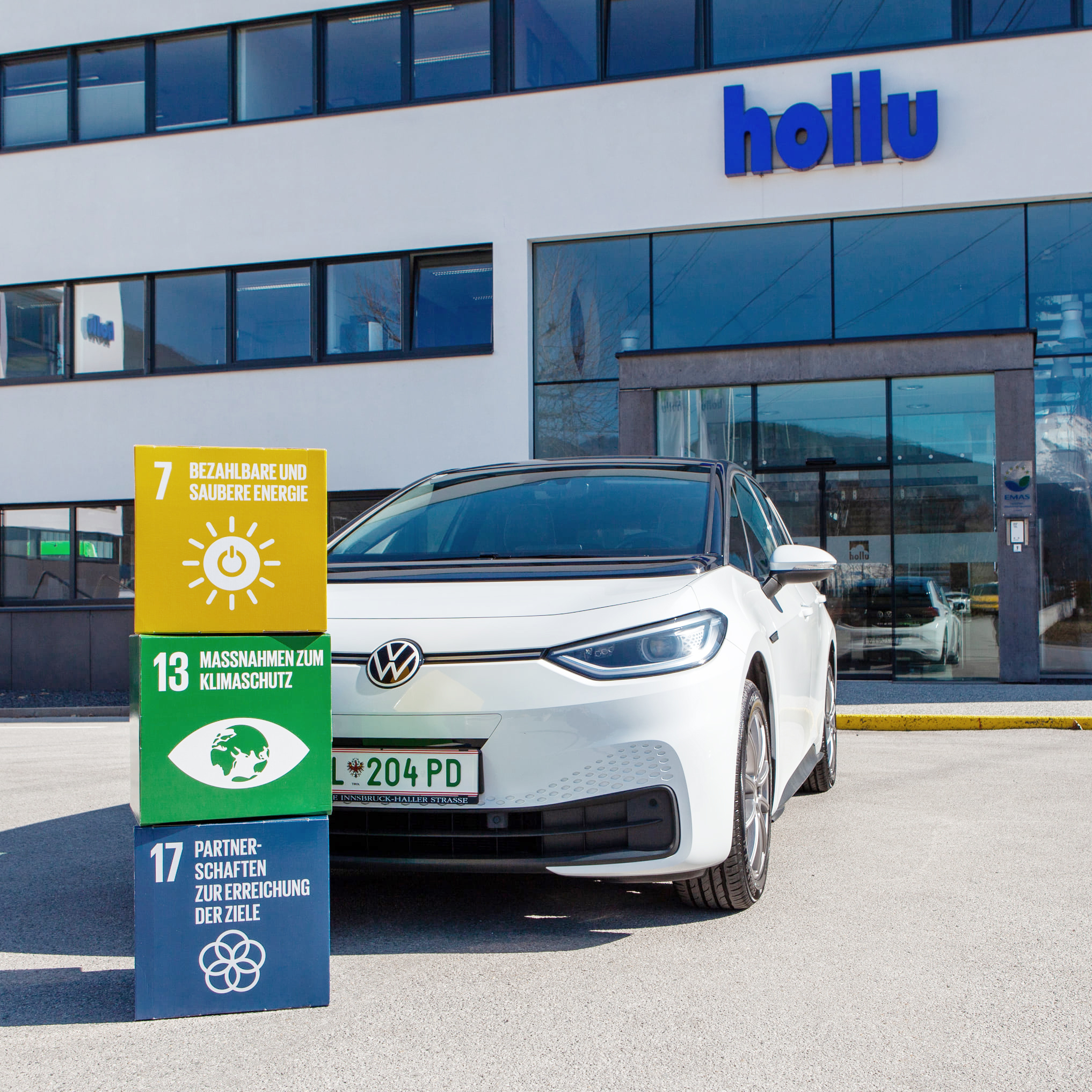 Ein Elektroauto mit bunten Würfeln vor einem weißen Gebäude.