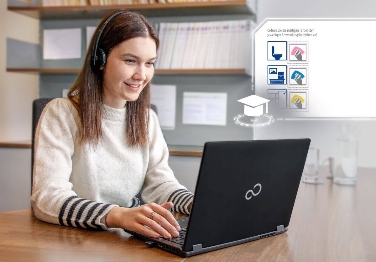 Eine Frau sitzt beim eLearning mit einem Laptop an ihrem Schreibtisch und trägt ein Headset.