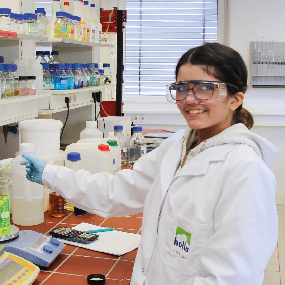 Eine junge Forscherin mit Schutzbrille in einem Labor.