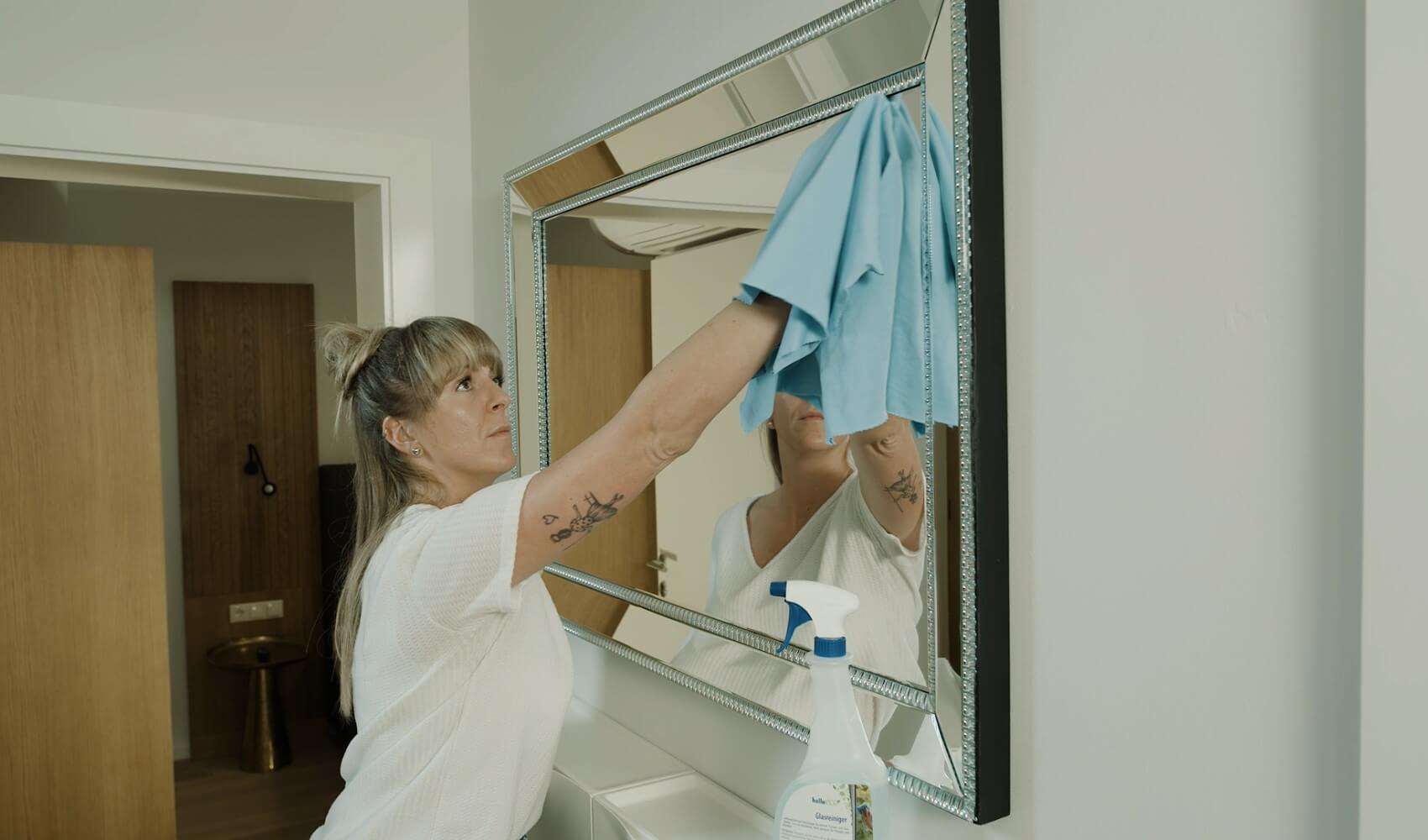 Ein Person reinigt einen Spiegel