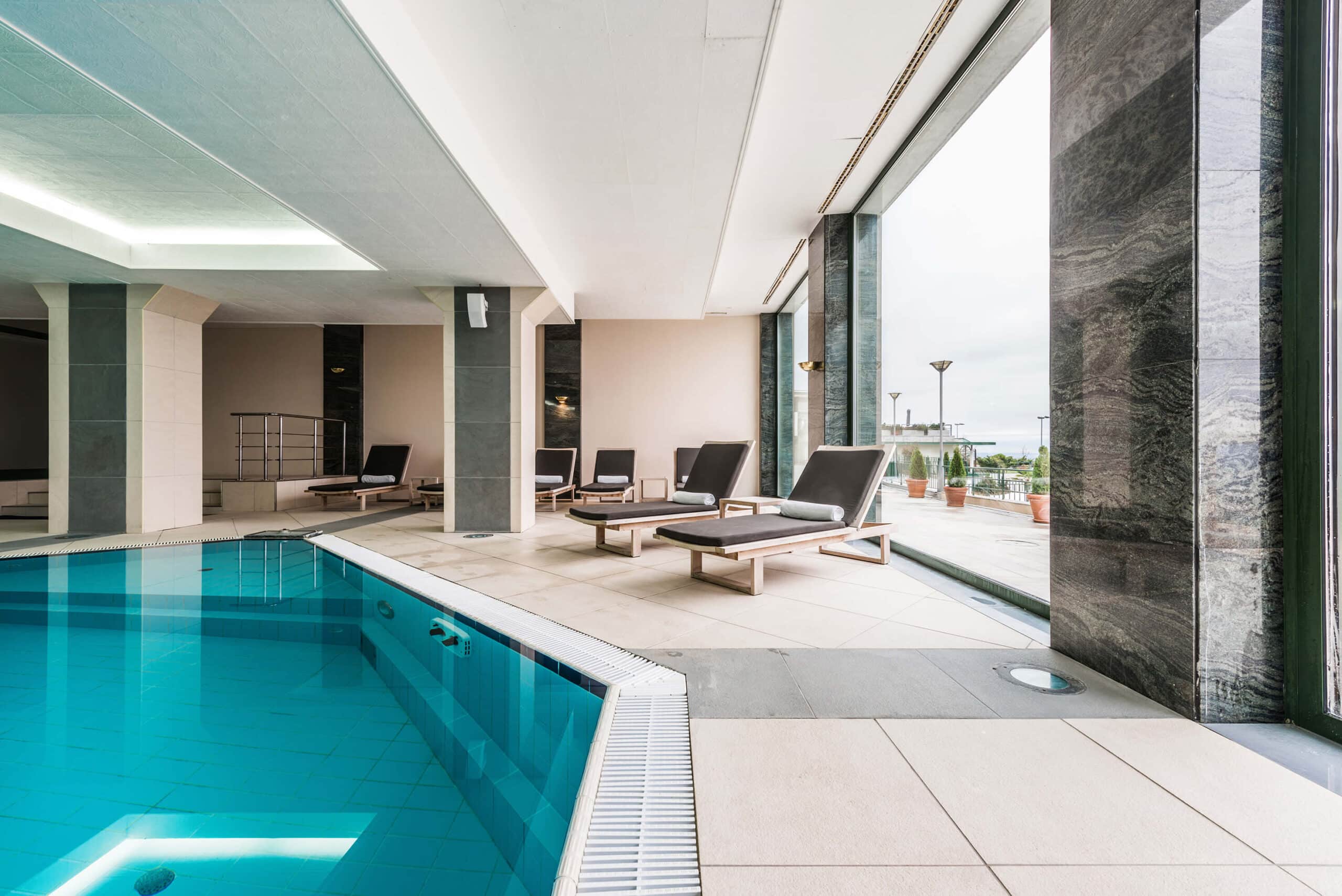 Bild vom einem Indoor-Hotelpool mit Schwimmbecken und Liegestüheln am Beckenrand